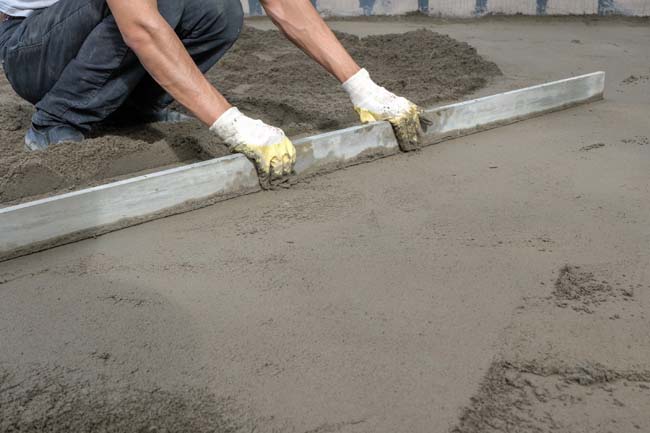 Construction worker leveling a concrete foundation